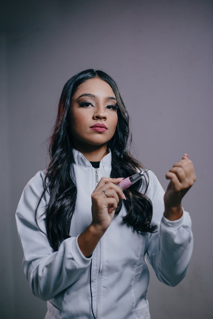 Young woman using a nail drill, showcasing beauty and professionalism in a studio setting.