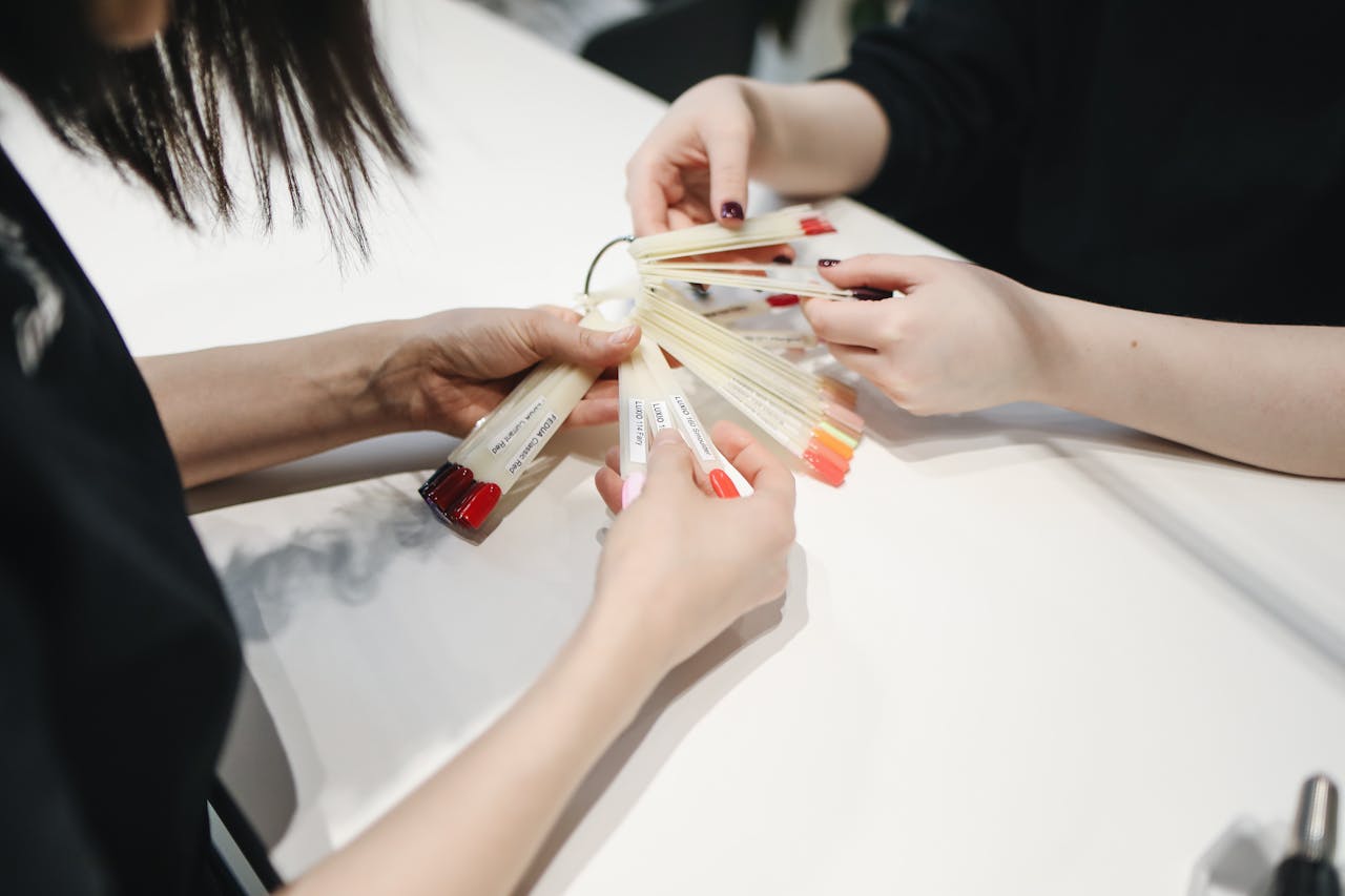 Close-up of hands selecting nail polish colors in a nail salon.